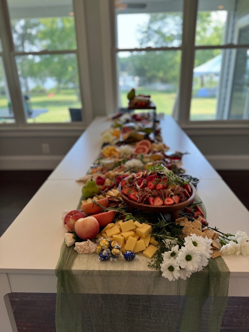 Long grazing table spread for an event with fresh fruits and flowers