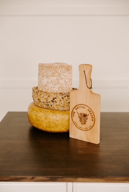 The Social Grazer branded cutting board with stacked artisan cheeses